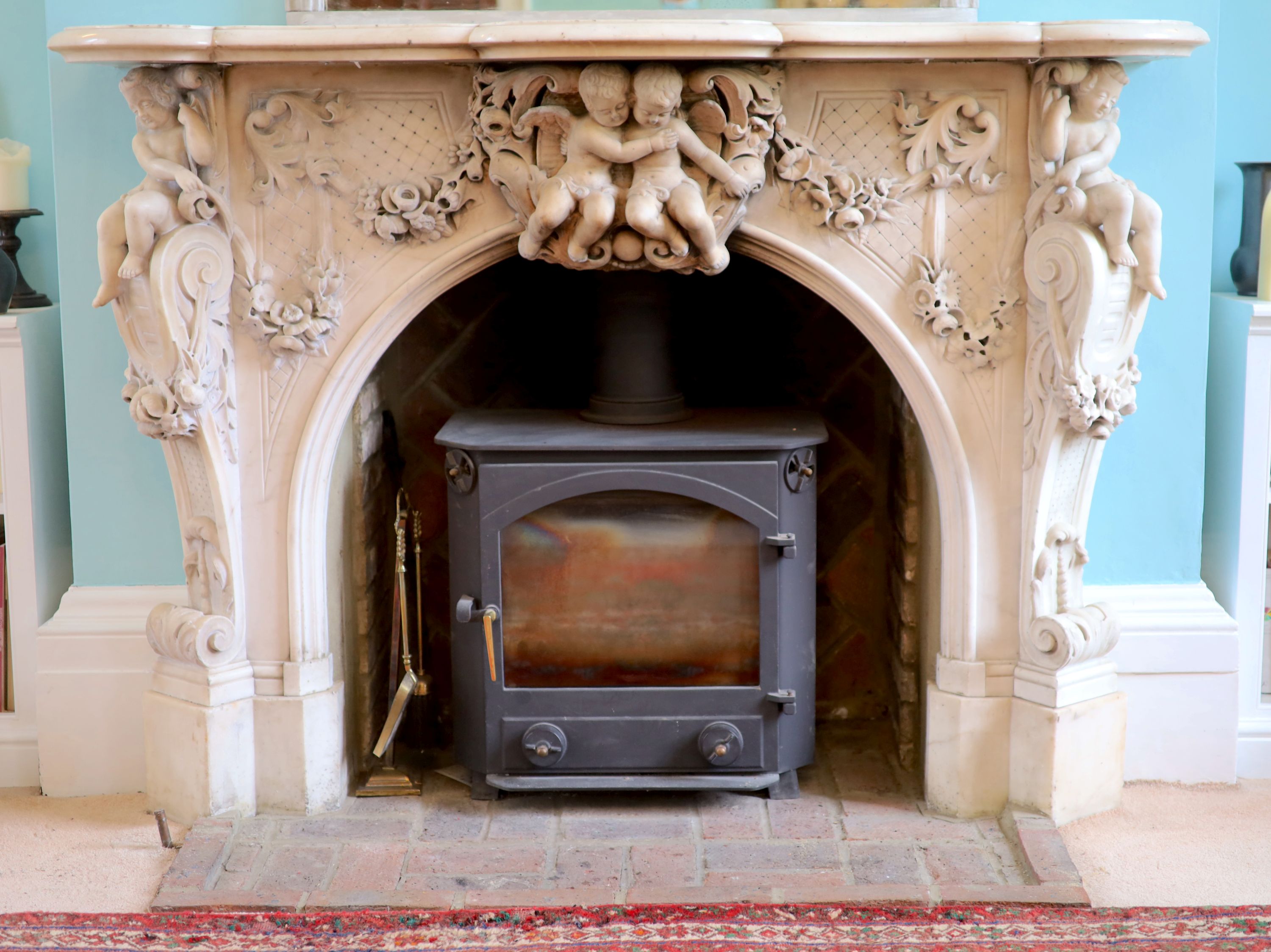 An important mid 19th century Italian white Carrara marble chimney piece, carved in the rococo taste, with seated putti, foliage swags